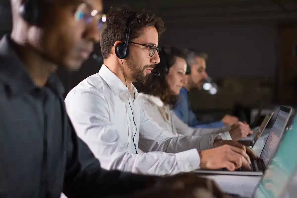 Profissionais de call center usando headsets e notebook enquanto trabalham em um ambiente de escritório, representando o impacto da automação nas profissões.