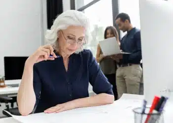 Mulher madura analisando documentos com foco e experiência, representando profissionais acima dos 40 anos no mercado de trabalho.