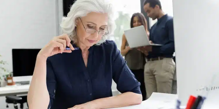 Mulher madura analisando documentos com foco e experiência, representando profissionais acima dos 40 anos no mercado de trabalho.