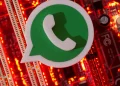 Logotipo do WhatsApp em 3D posicionado sobre placa-mãe com luzes vermelhas acesas, alertando sobre o perigo de crianças e adolescentes expostos em redes sociais