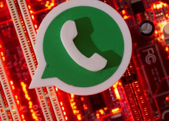 Logotipo do WhatsApp em 3D posicionado sobre placa-mãe com luzes vermelhas acesas, alertando sobre o perigo de crianças e adolescentes expostos em redes sociais