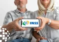 Casal de idosos segurando celular com logotipo do INSS durante retomada dos serviços do Meu INSS.