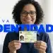 Mulher sorrindo enquanto segura a nova Carteira de Identidade Nacional do Brasil com a legenda 'Nova Identidade'.