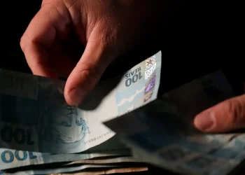 Pagamento de cédulas de real representando o depósito do 13º salário do INSS para diferentes beneficiários previsto para 2026.