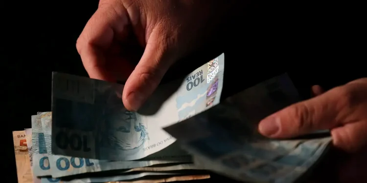 Pagamento de cédulas de real representando o depósito do 13º salário do INSS para diferentes beneficiários previsto para 2026.