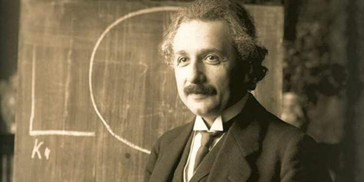 Albert Einstein diante de um quadro com fórmulas, físico conhecido pela teoria da relatividade e por reflexões sobre o sentido da felicidade.