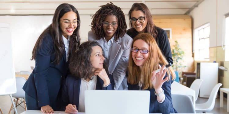 Mulheres profissionais reunidas no trabalho simbolizando a amizade feminina e o apoio que contribuem para o sucesso profissional.