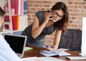 Profissional trabalhando no escritório, mostrando dedicação em sua tarefa enquanto interage com o chefe ou colega, tema de discussão sobre o impacto da bajulação no ambiente corporativo.