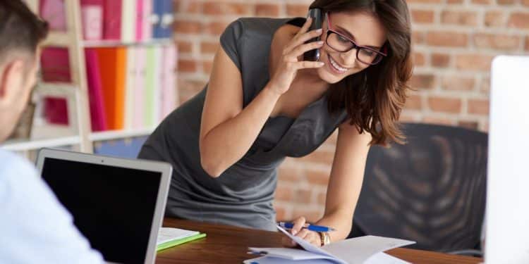 Profissional trabalhando no escritório, mostrando dedicação em sua tarefa enquanto interage com o chefe ou colega, tema de discussão sobre o impacto da bajulação no ambiente corporativo.