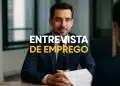 Homem em entrevista de emprego, sentado à mesa, com terno e gravata.