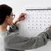 Mulher observando calendário na parede.