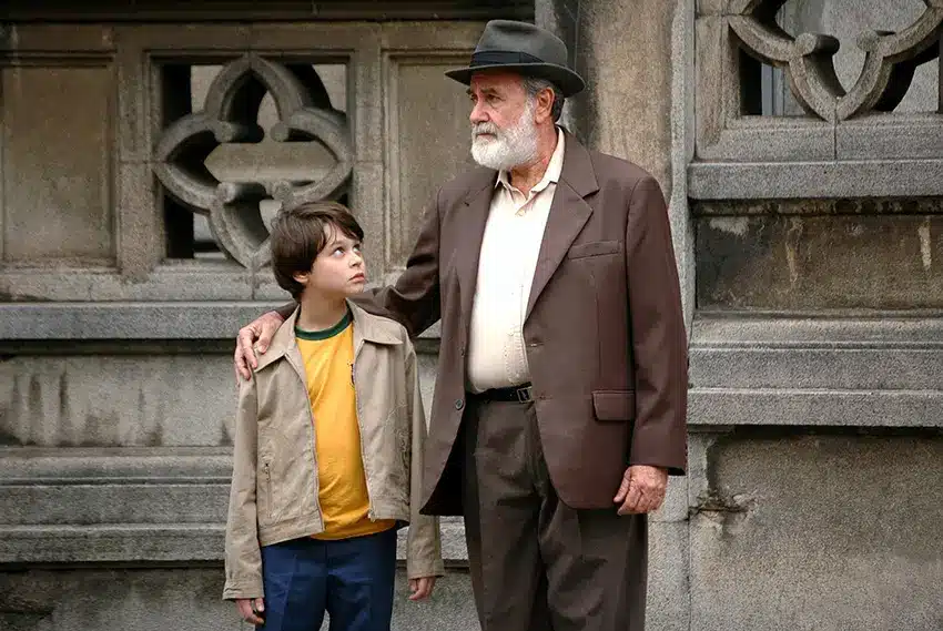 Garoto e idoso caminhando juntos em cena do filme O Ano em que Meus Pais Saíram de Férias ambientado durante a ditadura militar.