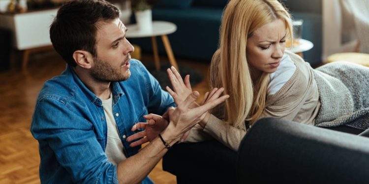 Casal discutindo na sala de casa, demonstrando tensão emocional causada por falhas na comunicação.