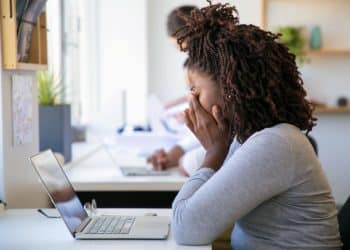 Mulher com expressão de cansaço no trabalho, simbolizando os efeitos da depressão nas profissões brasileiras em 2026.