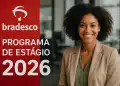 Jovem profissional sorrindo em escritório ao lado de painel vermelho do Programa de Estágio Bradesco 2026.