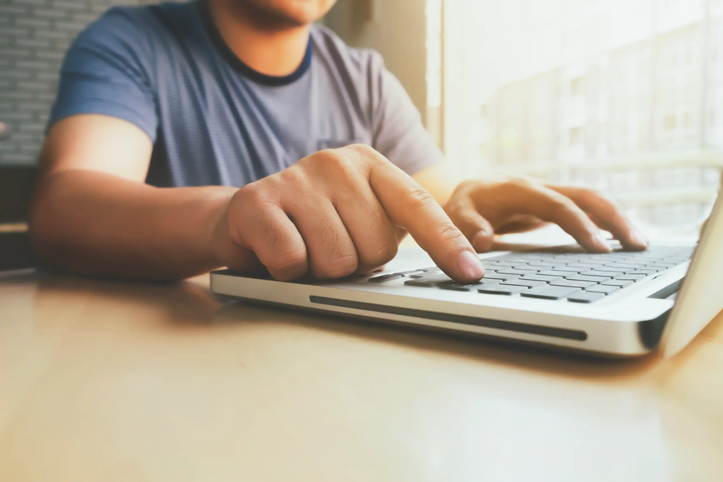 Pessoa digitando no laptop, ilustrando o momento de inscrição no concurso público.