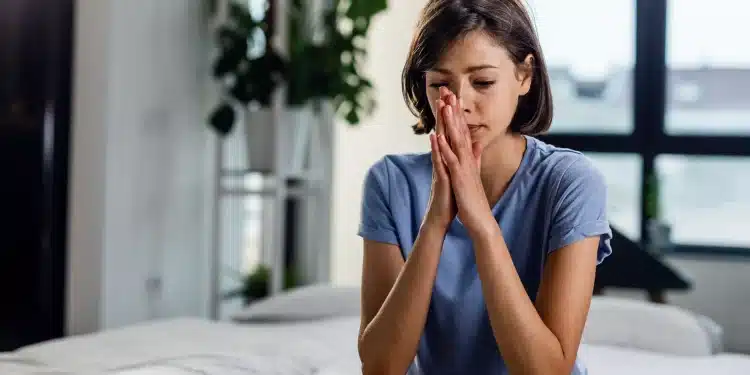 Pessoa com expressão de ansiedade sentada na cama, simbolizando o sentimento de apreensão que atinge muitas pessoas nas noites de domingo.