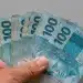 Notas de 100 reais representam a possível antecipação do décimo terceiro salário para beneficiários do INSS.
