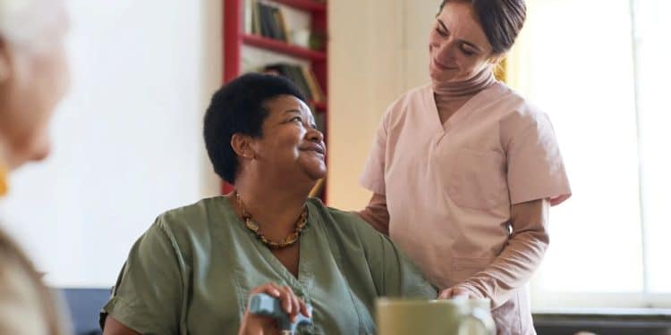 Mulher assistente de saúde cuidando de paciente em lar de idosos, destacando o papel das mulheres em profissões com salários mais altos do que os homens.