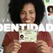 Emissão gratuita CIN: mulher negra sorrindo segurando a nova Carteira de Identidade Nacional com texto Nova Identidade em destaque