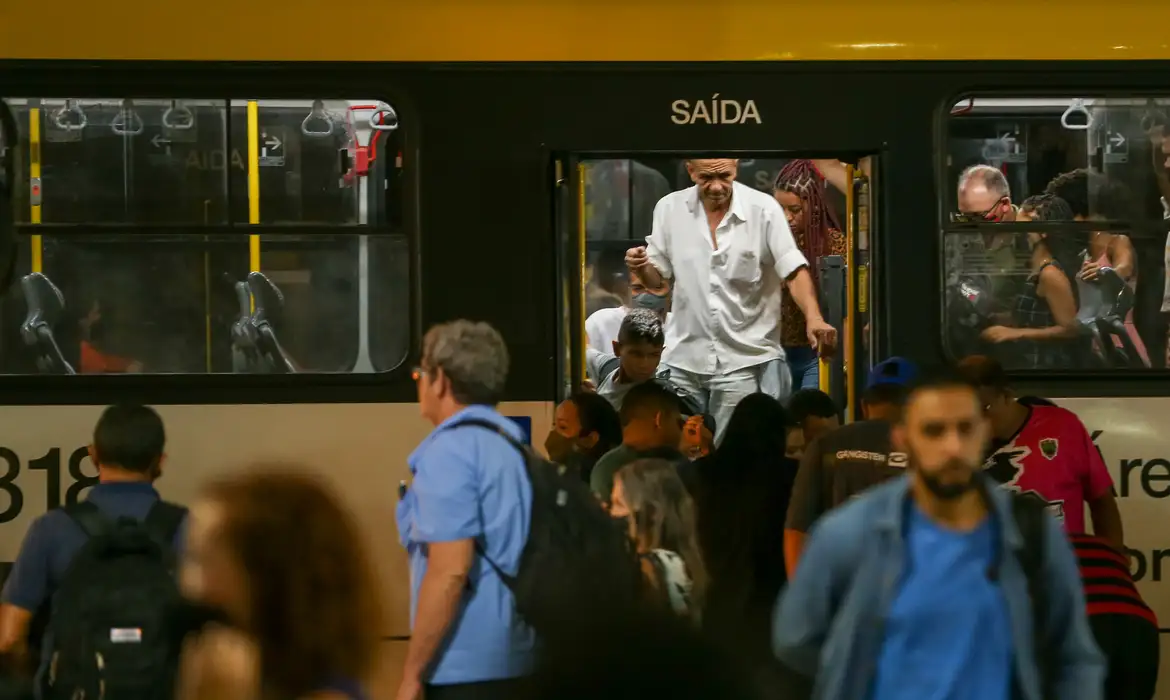 Pessoas desembarcando de ônibus lotado em terminal urbano, representando o cotidiano intenso do transporte público onde atitudes empáticas como ceder o lugar promovem bem-estar e conexão entre desconhecidos