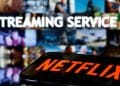 Close-up de um smartphone exibindo o logotipo da Netflix em uma tela brilhante, com foco na interface do aplicativo de streaming.