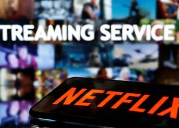 Close-up de um smartphone exibindo o logotipo da Netflix em uma tela brilhante, com foco na interface do aplicativo de streaming.