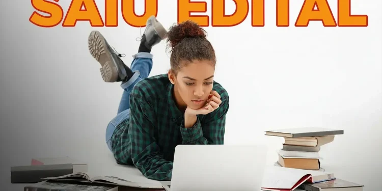 Jovem estudando no computador enquanto lê livros, anunciando novo concurso com 80 vagas e salários de até R$ 9,6 mil.