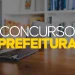 Notebook sobre mesa ilustrando concurso público municipal com 418 vagas para níveis fundamental, médio e superior