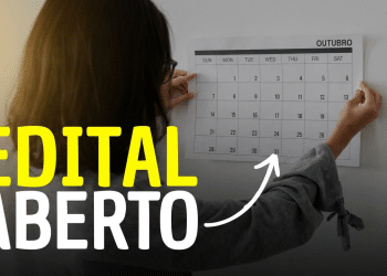 Pessoa marca datas no calendário de outubro em parede branca indicando abertura de edital