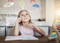 Menina loira com expressão pensativa sentada à mesa com caderno, cercada por desenhos flutuantes de fórmulas matemáticas, planetas e uma lâmpada acesa, simbolizando inteligência e criatividade infantil.