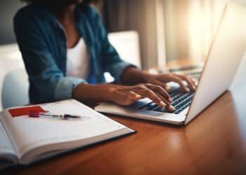 Pessoa digitando em notebook enquanto estuda curso online de inteligência artificial com anotações ao lado.