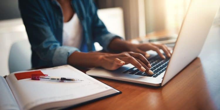 Pessoa digitando em notebook enquanto estuda curso online de inteligência artificial com anotações ao lado.