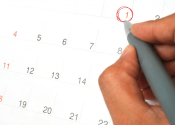 Mão circulando o dia primeiro em calendário com caneta cinza