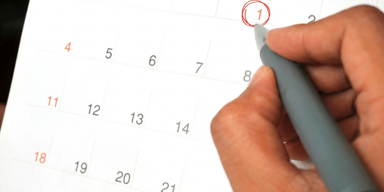 Mão circulando o dia primeiro em calendário com caneta cinza