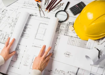 Plano de construção com ferramentas de engenharia, como régua, compasso e lupa, representando o trabalho de um engenheiro.