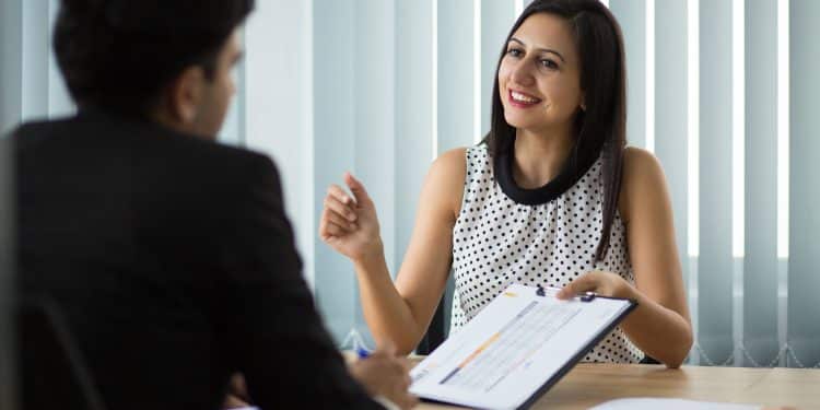 Candidata conversando com recrutador durante entrevista de emprego, segurando currículo e demonstrando confiança e autenticidade