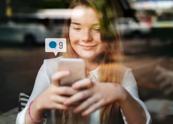 Pessoa usando smartphone com ícones de redes sociais em destaque, representando a influência do algoritmo nas decisões de carreira