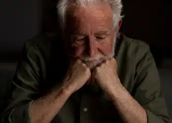 Homem idoso pensativo apoiando o rosto nas mãos, representando cansaço emocional após anos sendo o apoio de outras pessoas.