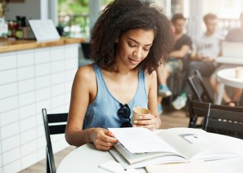Mulher estudando disciplinas essenciais para concursos públicos em café
