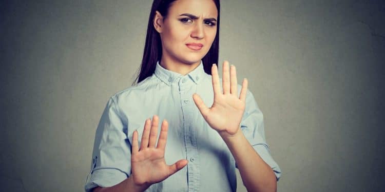 Mulher com expressão de desagrado e mãos levantadas em sinal de recusa, representando insegurança nas interações sociais.