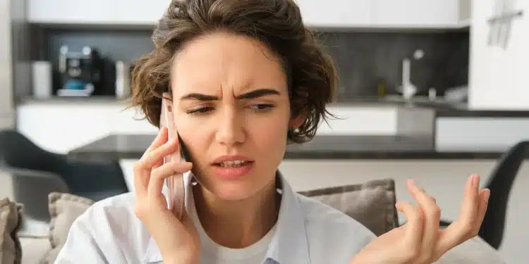Mulher com expressão preocupada falando ao telefone após receber ligação suspeita de falso gerente de banco, golpe alertado pela Febraban.