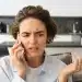 Mulher com expressão preocupada falando ao telefone após receber ligação suspeita de falso gerente de banco, golpe alertado pela Febraban.