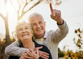 Casal de idosos sorrindo ao ar livre representa bem-estar e mudanças positivas após os 60 anos.