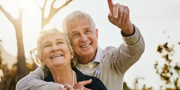 Casal de idosos sorrindo ao ar livre representa bem-estar e mudanças positivas após os 60 anos.