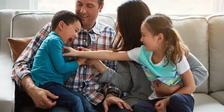 Família brincando juntos no sofá, representando os comportamentos comuns em adultos que foram o filho favorito durante a infância.