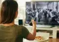 Mulher assistindo a filme sobre a Revolução Industrial, com foco em trabalhadores operando máquinas.