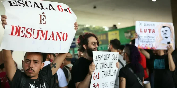 Protesto contra a escala 6x1 no Brasil com manifestantes segurando cartazes que criticam a jornada de trabalho considerada desumana.