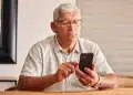 Idoso utilizando smartphone em casa, representando o medo de golpes digitais entre pessoas acima de 60 anos em São Paulo.