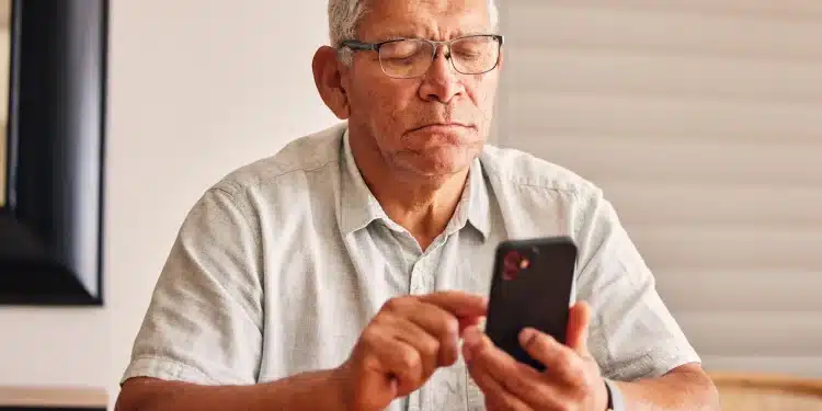 Idoso utilizando smartphone em casa, representando o medo de golpes digitais entre pessoas acima de 60 anos em São Paulo.